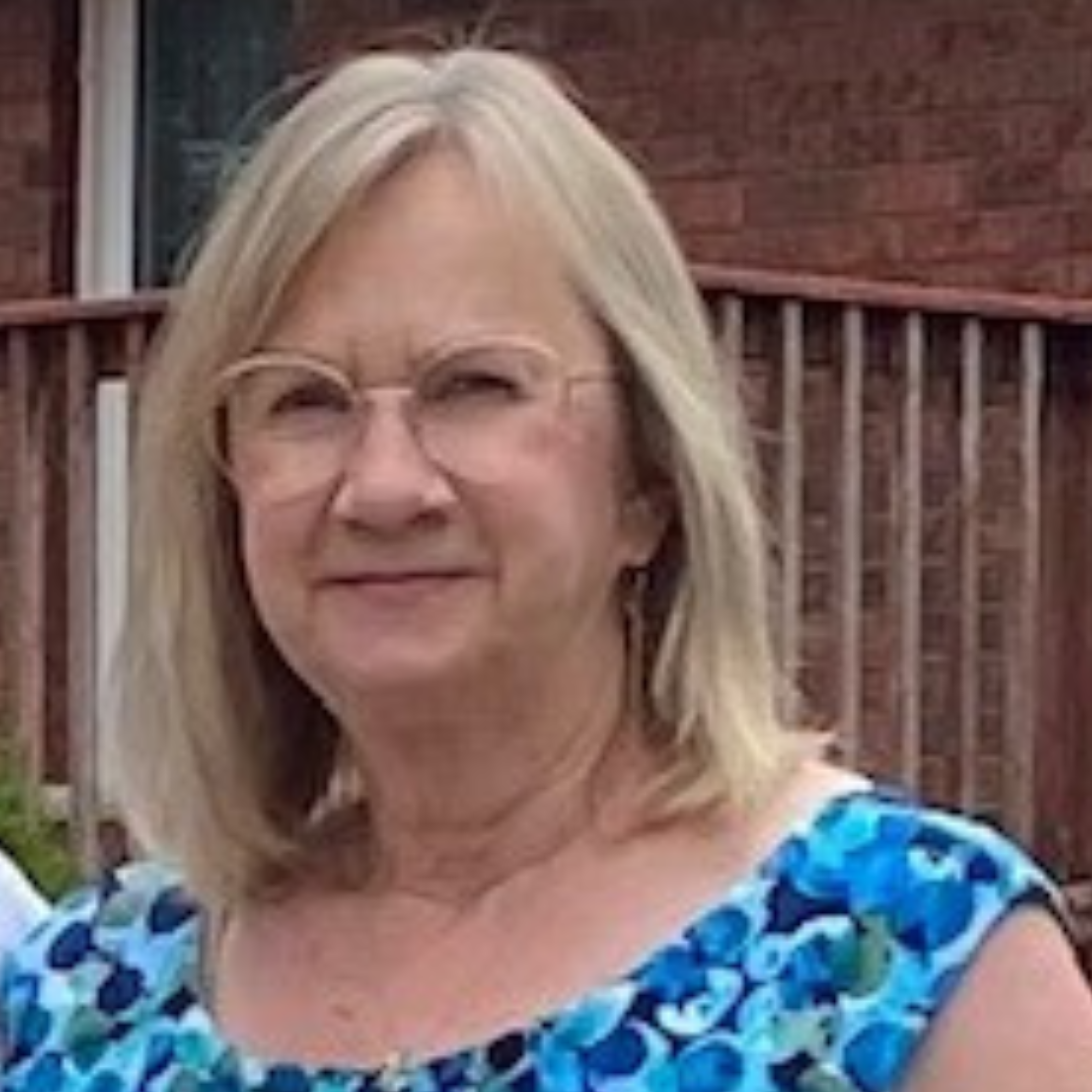 Susan is in her front yard smiling for a photo.